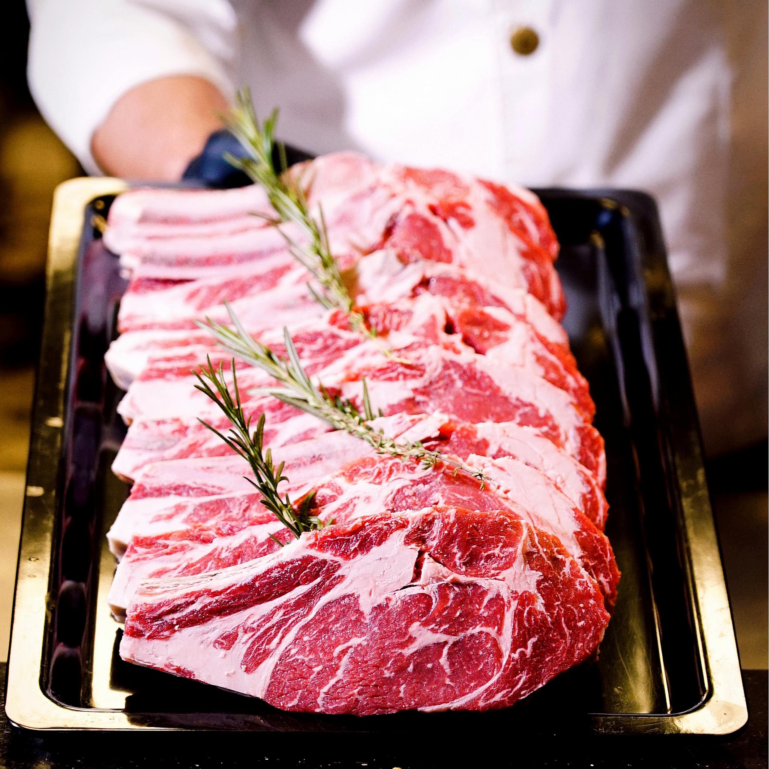 Close-up of raw lamb chops garnished with rosemary, perfect for culinary themes.