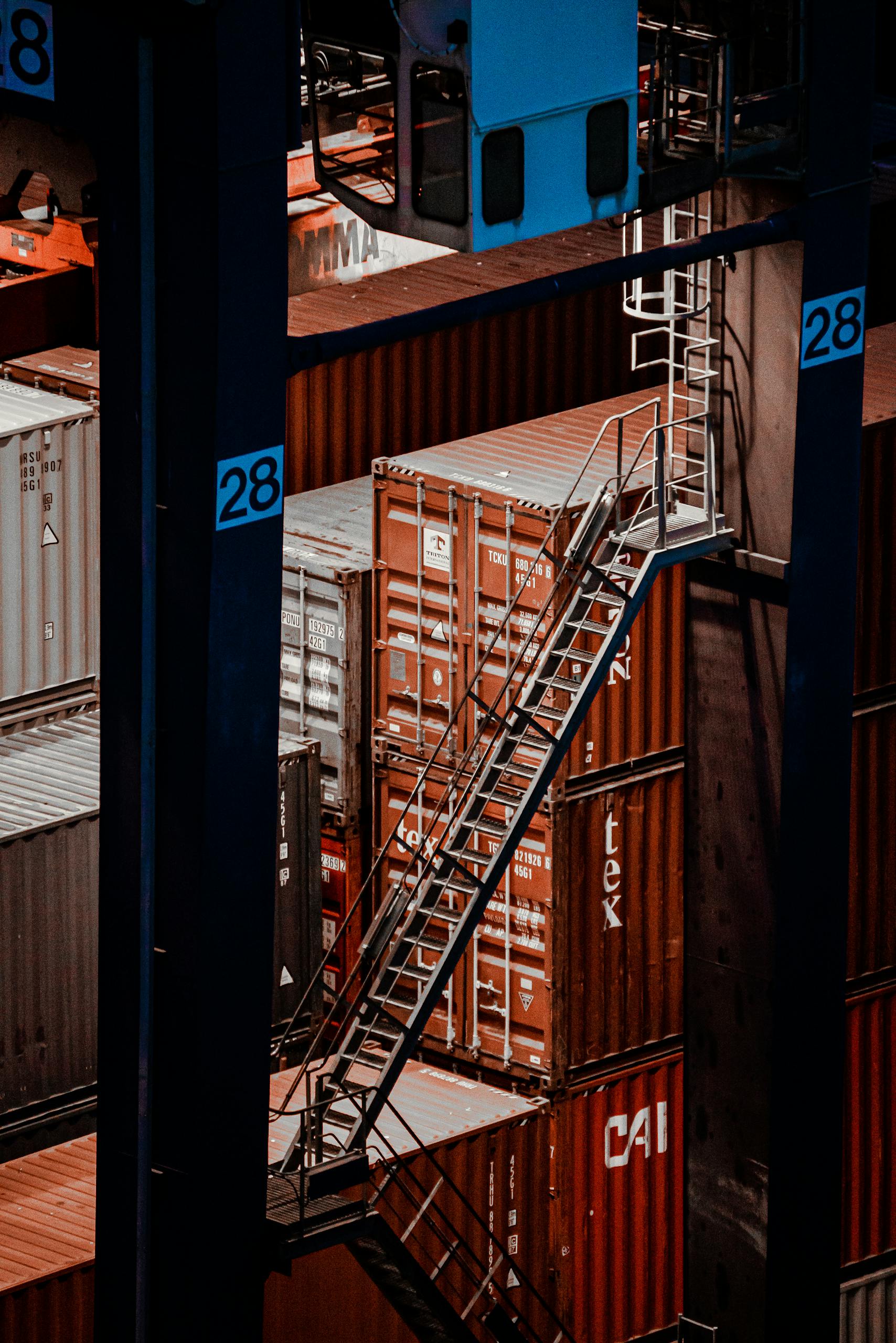 Elevated view of cargo containers with a metal staircase at a shipping facility.